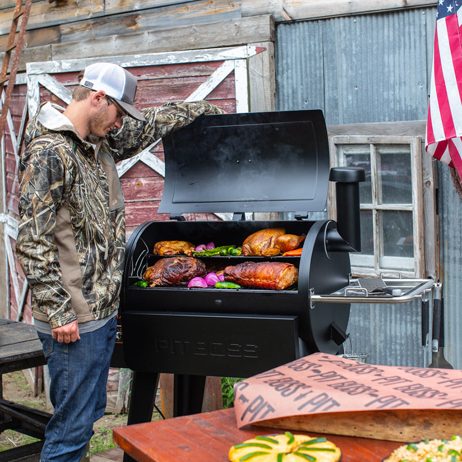 man opening pit boss sportsman 820 wood pellet grill with wifi. grill is filled with smoked foods