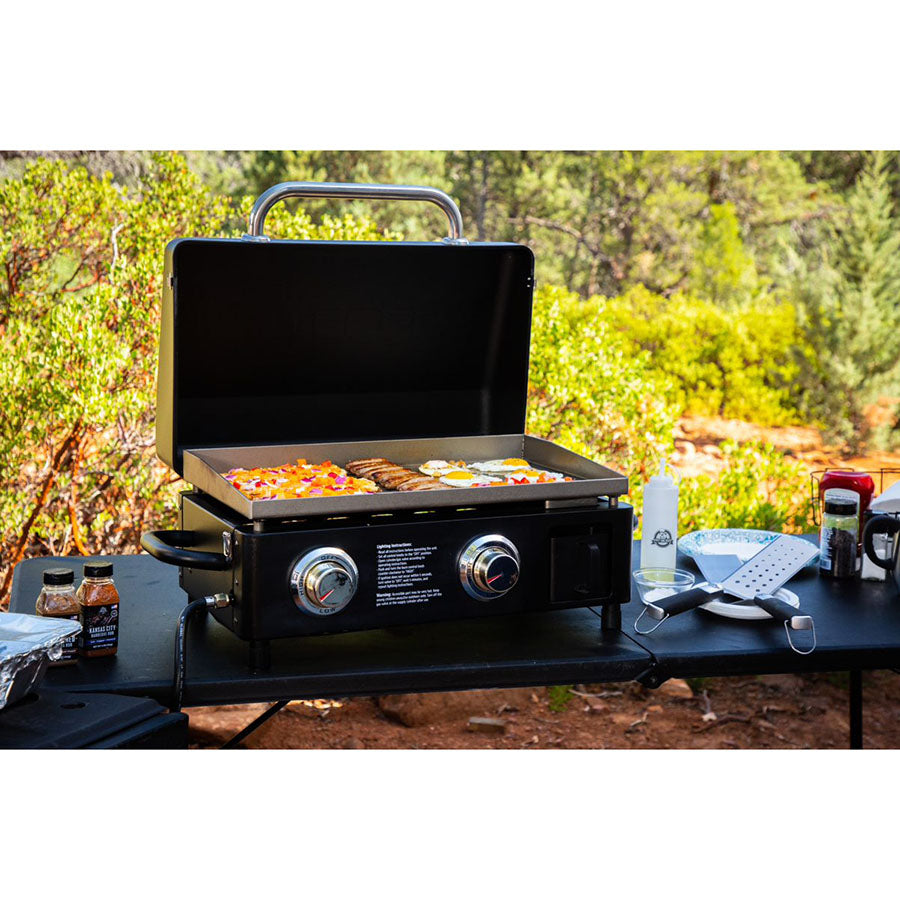 griddle with food sitting on picnic table with other Pit Boss grilling accessories