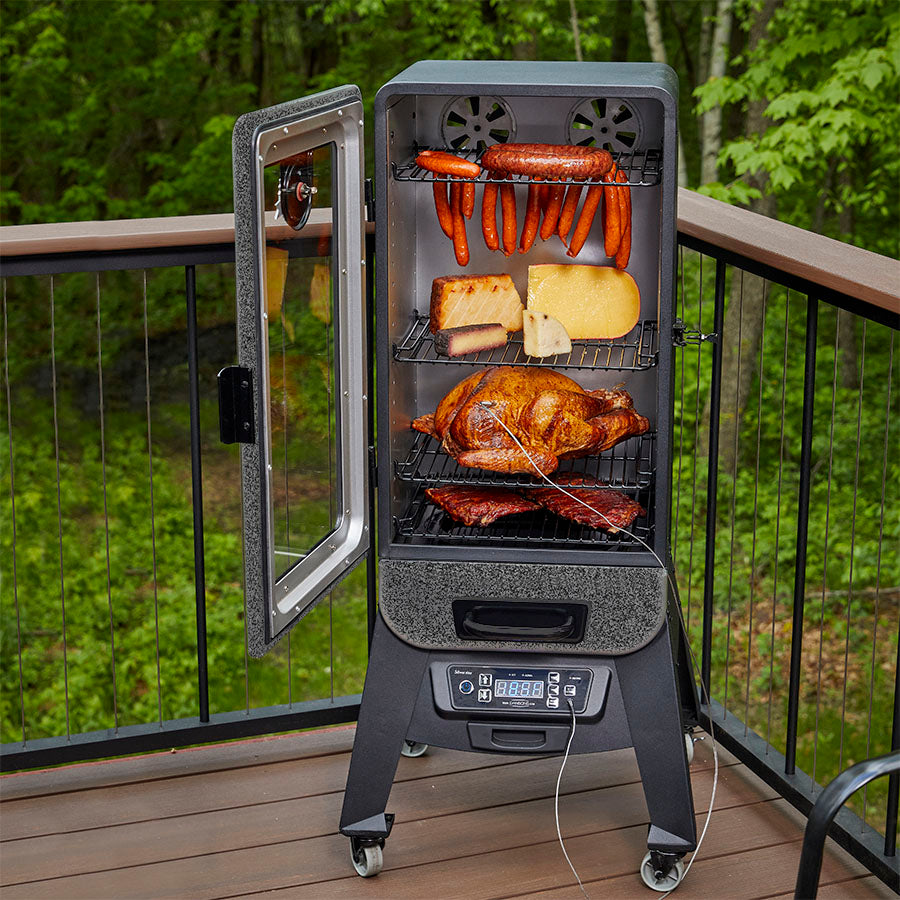 Meats and cheeses inside smoke. Meat probe being used. Door open of the smoker. Displayed outside