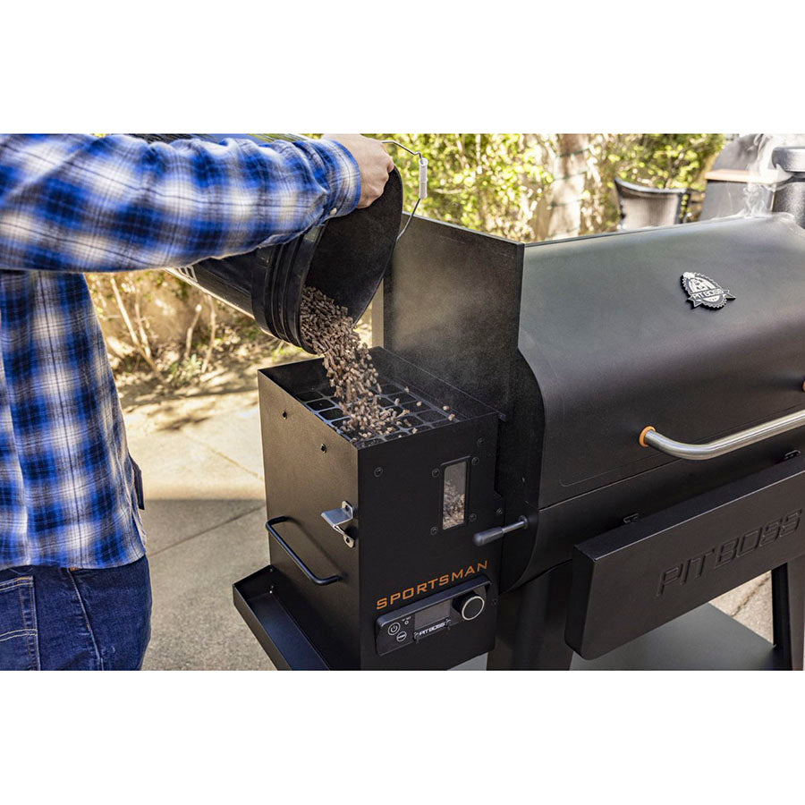 Grill standing in a backyard. Man pouring 100% hardwood pellets into grill