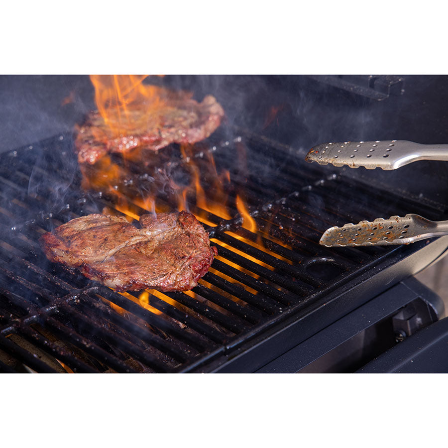 up close of steak cooking on grill with open flame and smoke