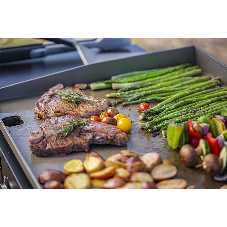 up close lifestyle of steak and asparagus cooking on griddle top