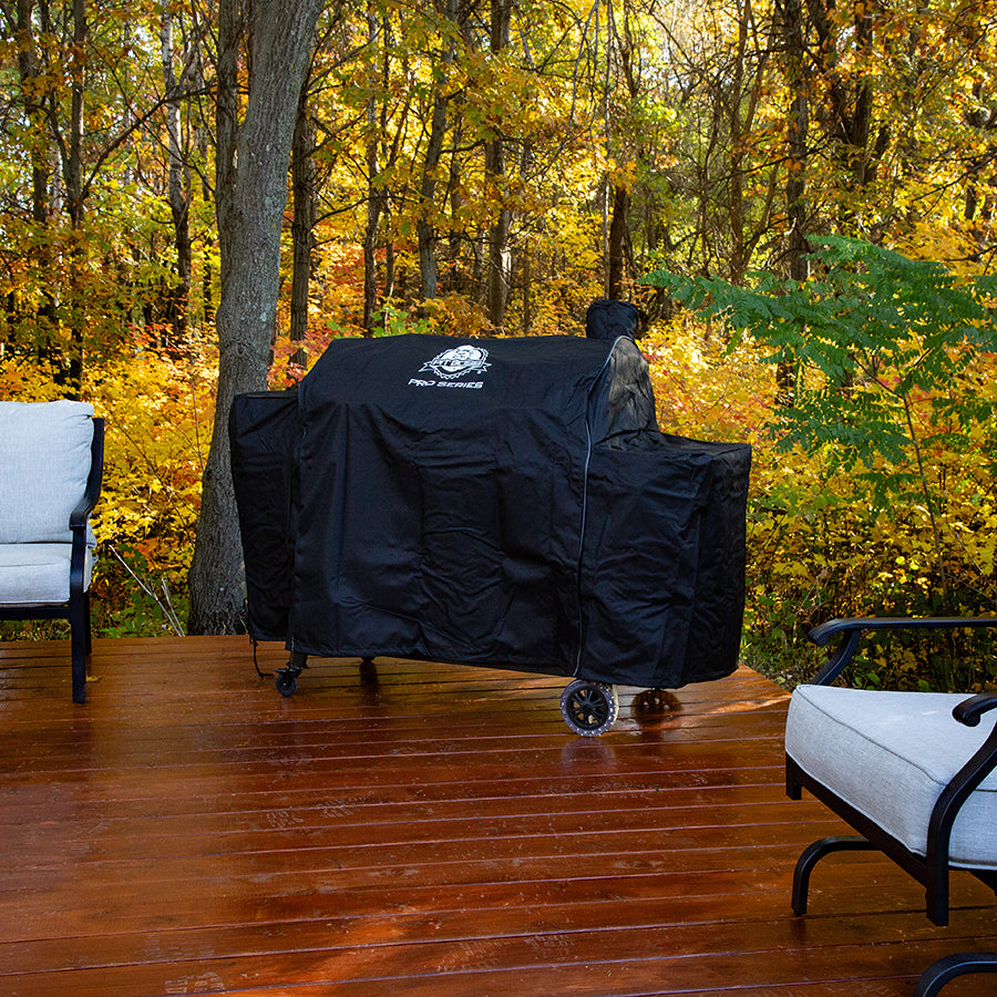 lifestyle_1, black grill bag with white pit boss logo on top. Pictured on rainy porch with bright fall forest in background