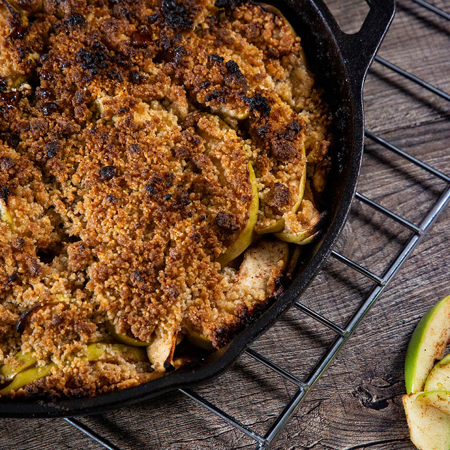 black round cast iron skillet with apple crumble inside