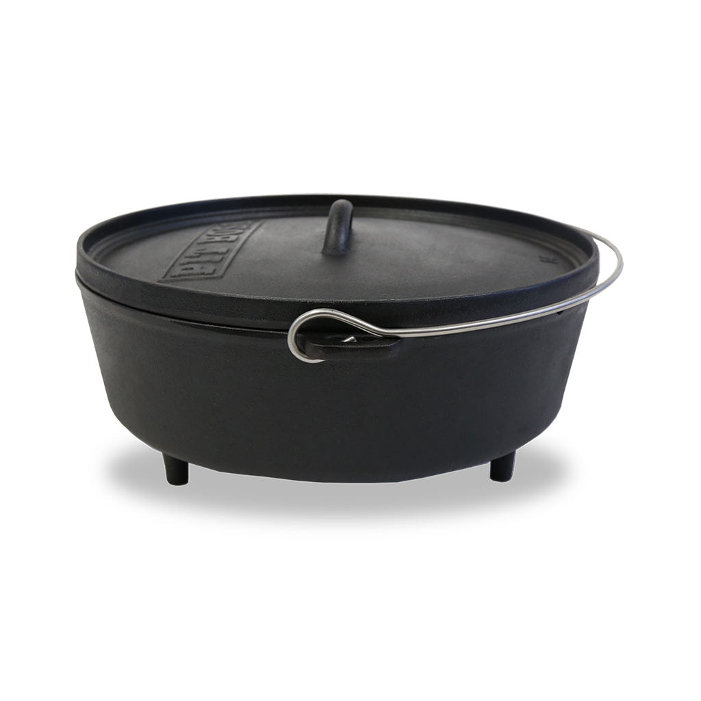 lifestyle_2, Round, black dutch oven with feet and loops with metal handle. Angled view