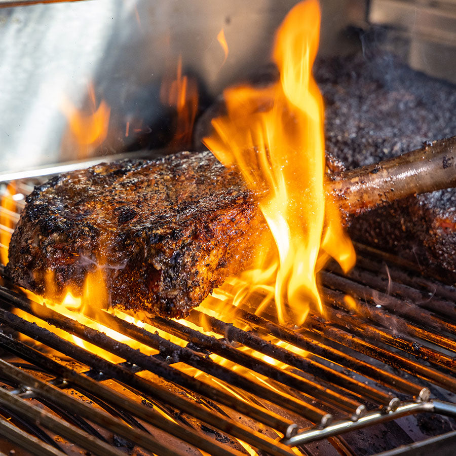 up close of steak being seared in open flame on grill rack
