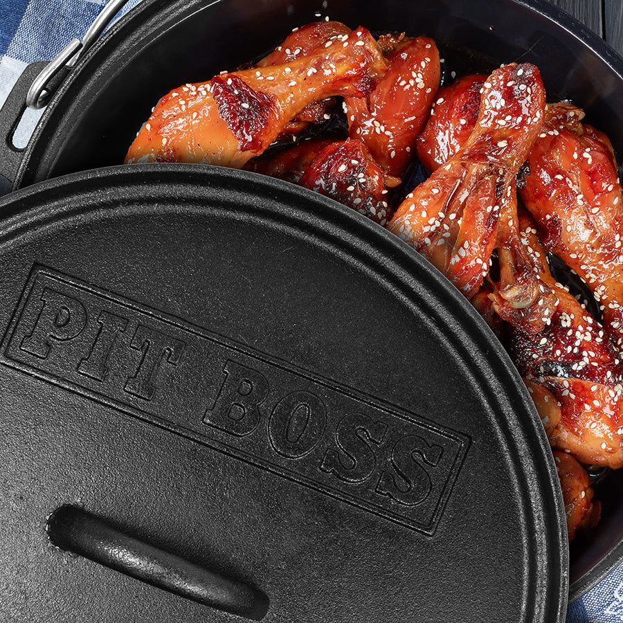 Black cast iron dutch oven with Pit Boss logo. Smoked chicken wings inside dutch oven